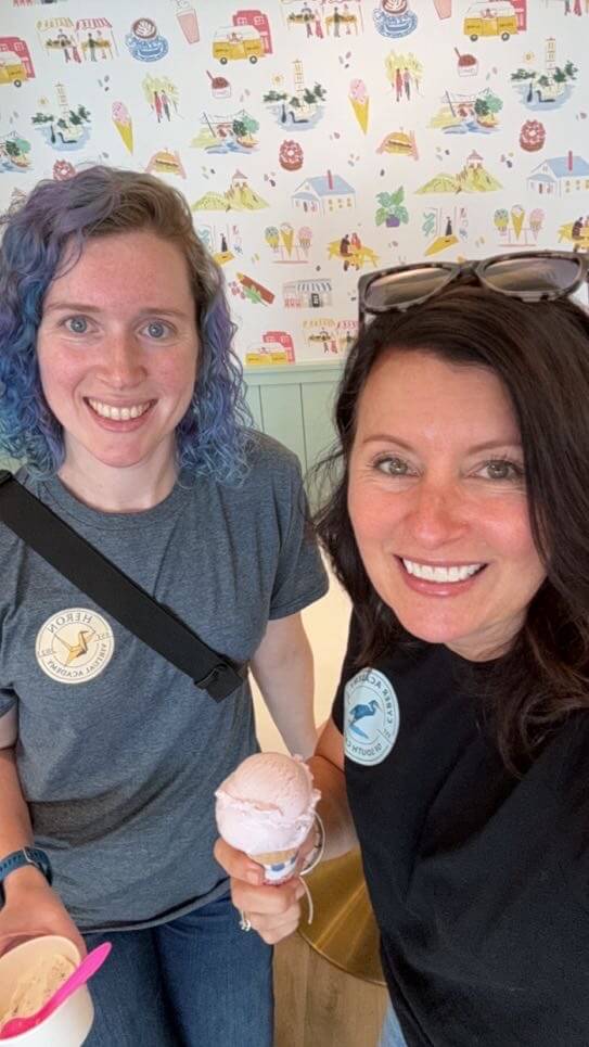 Two women smiling and holding ice cream cones.