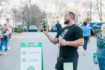 One man smiling while taking a picture with his phone