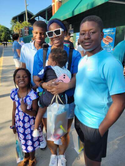 A smiling family enjoys a sunny day at a stadium.