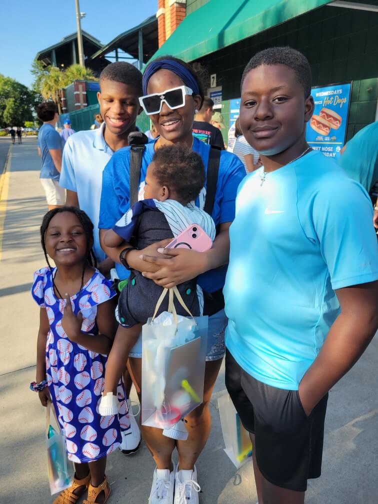 A smiling family enjoys a sunny day at a stadium.
