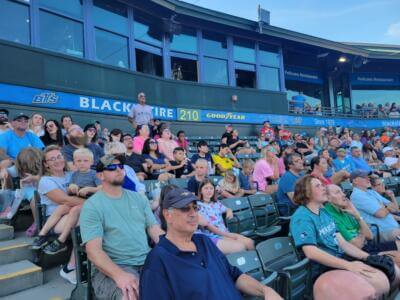 A large crowd of people sits in stadium seats, watching an event with focused expressions.