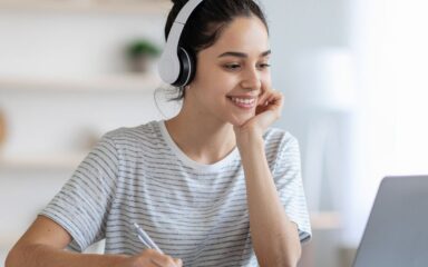 Student wearing a white pair of headphones while working with her laptop