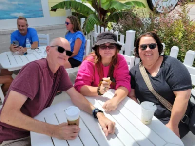 Three people outdoors drinking coffee