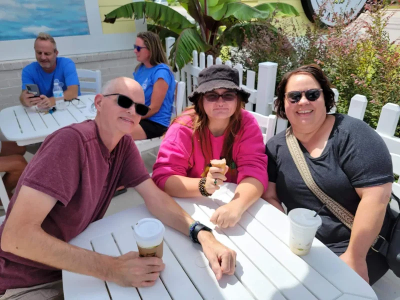 Three people outdoors drinking coffee