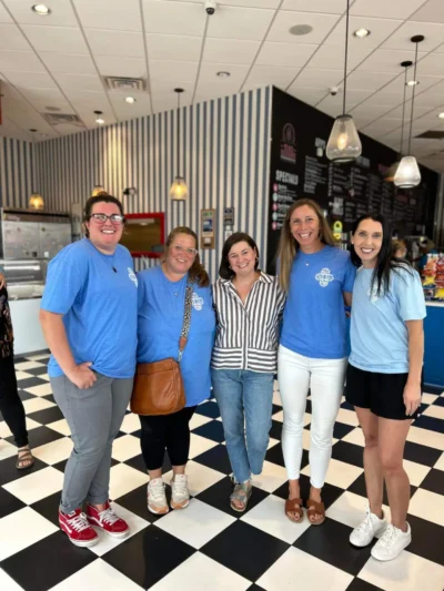 Five women smile in a bright ice cream shop