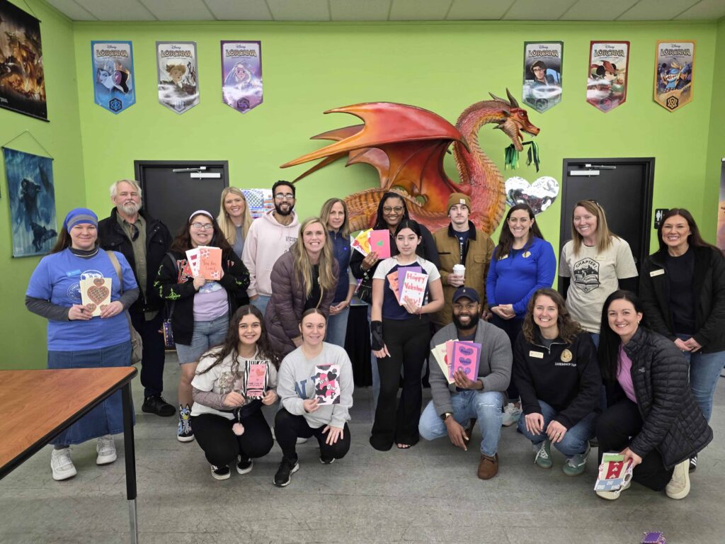 Group of people smiling in front of a green wall