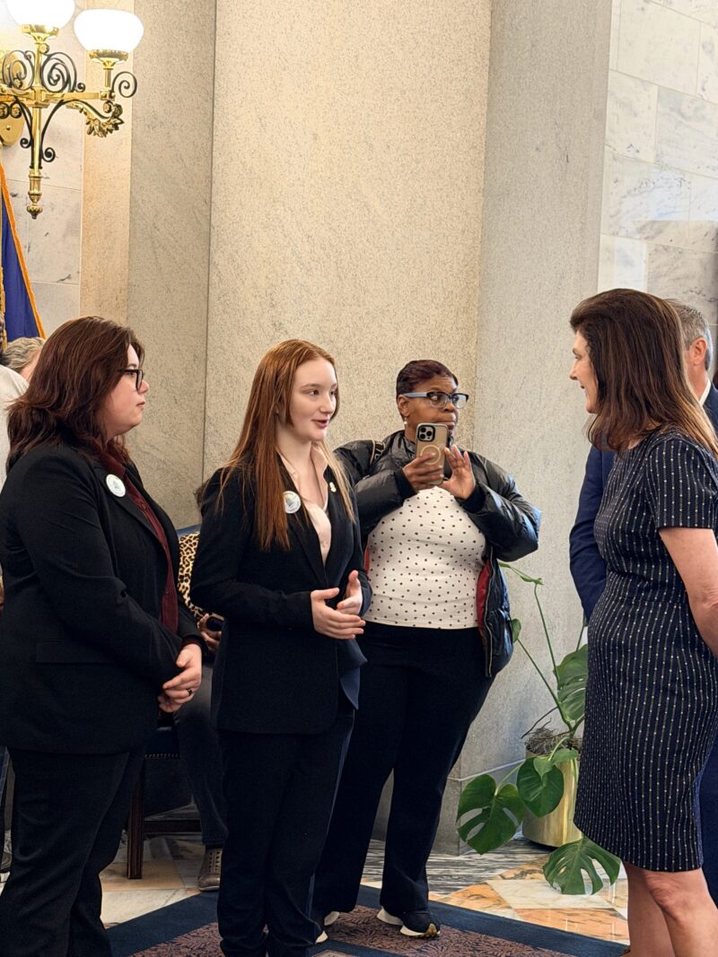 Several women in business attire are engaged in conversation in a formal setting.