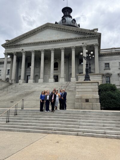 A group of people stands on the steps of a grand neoclassical building