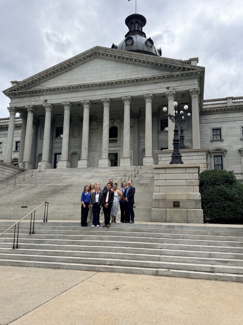 A group of people stands on the steps of a grand neoclassical building